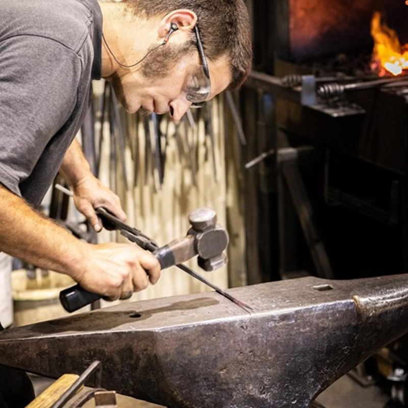 Artisan en ferronnerie d’art au travail, démontrant une technique traditionnelle dans un environnement visuel clair